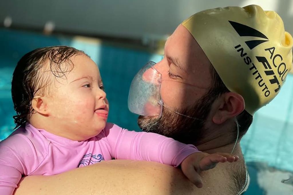 Instrutor e criança pequena praticando natação terapêutica no Instituto Acqua Fitt