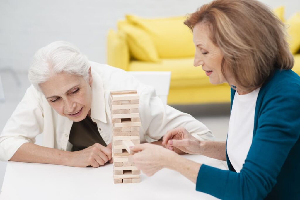 Duas idosas jogando juntas para auxiliar no desenvolvimento psicomotor.