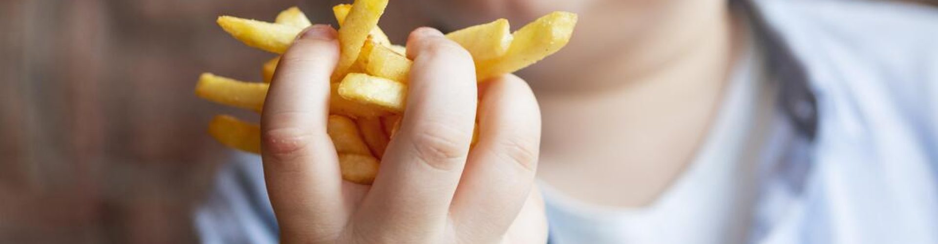 Criança comendo alimentos que podem causar obesidade infantil.